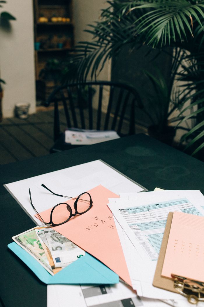 An arranged office desk with eyeglasses, documents, and plants around, conveying a professional and organized space.